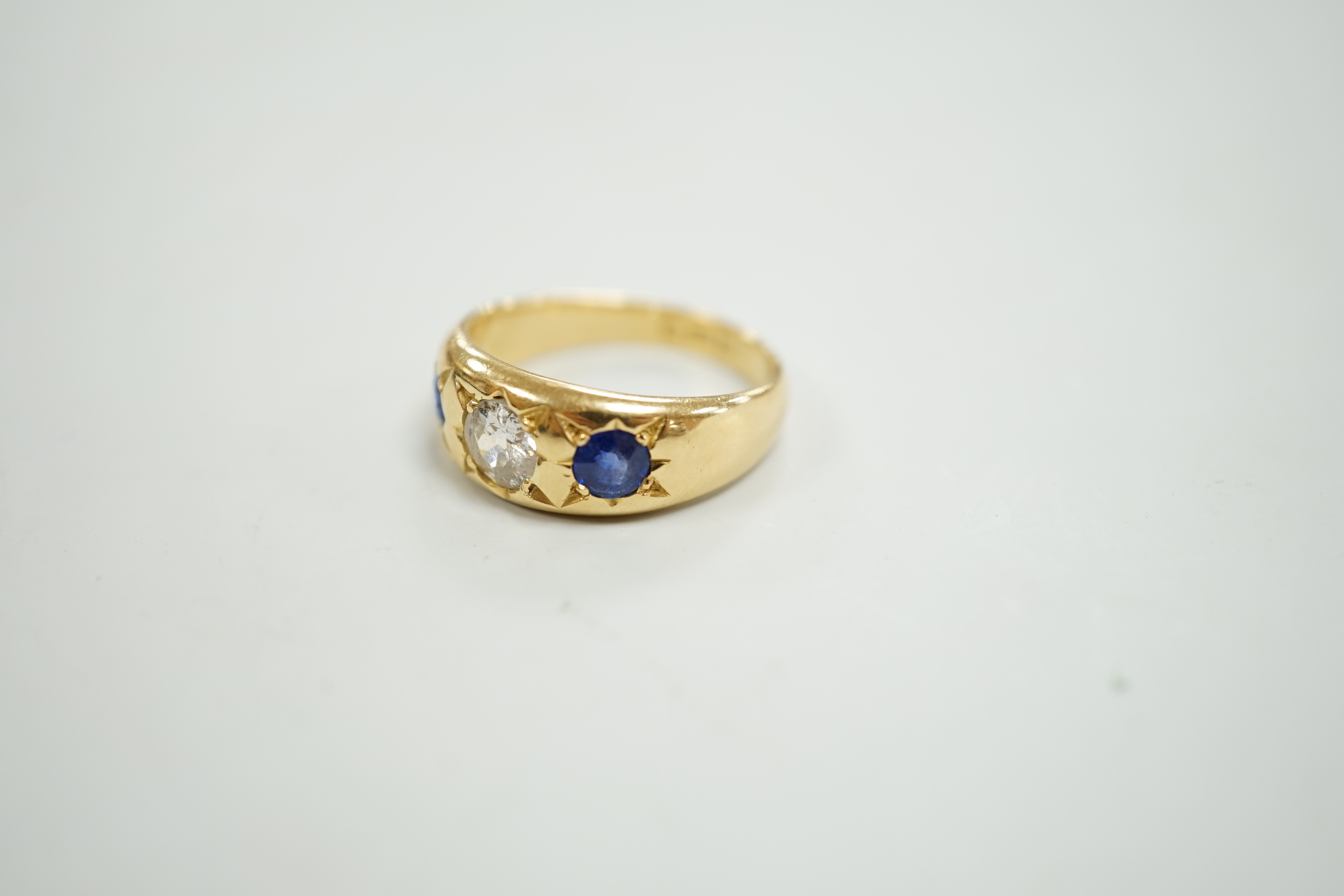 An early 20th century 18ct gold and gypsy set single stone diamond and two stone sapphire set ring, size O, gross weight 6.4 grams.